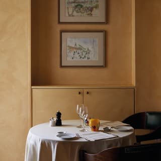 Circular table in atmospheric lowlight with wine glasses and curved wooden chairs
