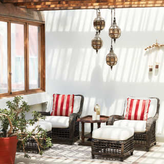 Two wicker chairs with matching foot rests and vibrant red-striped cushions beneath bare wood beams