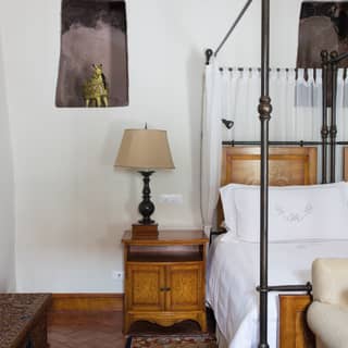 Hotel room bedside table with a carved wooden lamp and artwork above