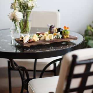 Elaborate cheese platter on a circular glass table with white rose centerpiece