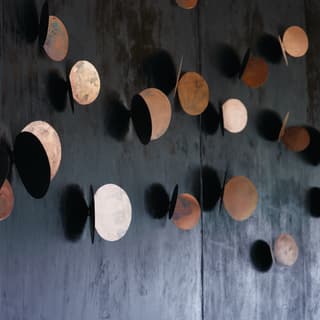 Close-up of a bar wall with dark black walls and copper circle details