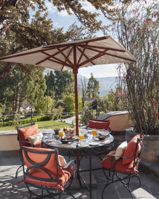Circular table on an outdoor patio, surrounded by red cushioned chairs
